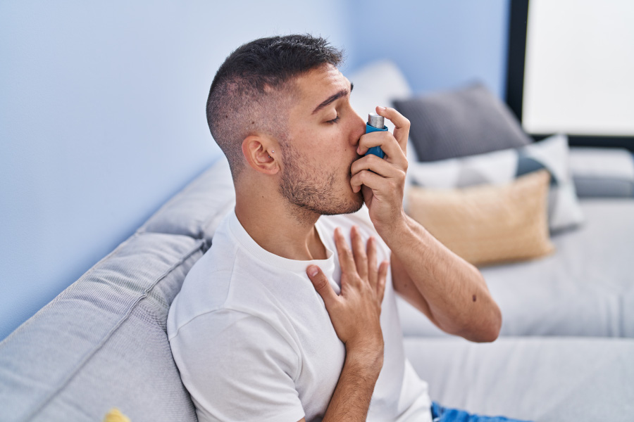 young-hispanic-man-using-inhaler-sitting-sofa-home-900