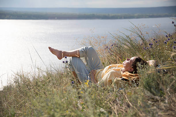강가에 누워 디지털 디톡스를 실천하고 있는 여자