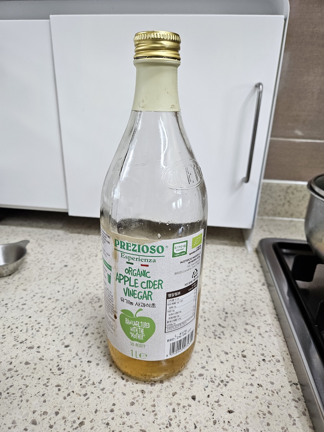 7년 동안 아침 공복 루틴으로 꾸준히 마신 PREZIOSO 유기농 애플사이다비니거(사과식초) 1L 제품 사진. 주방 조리대에 놓인 상태로, 건강관리 습관을 보여주는 장면