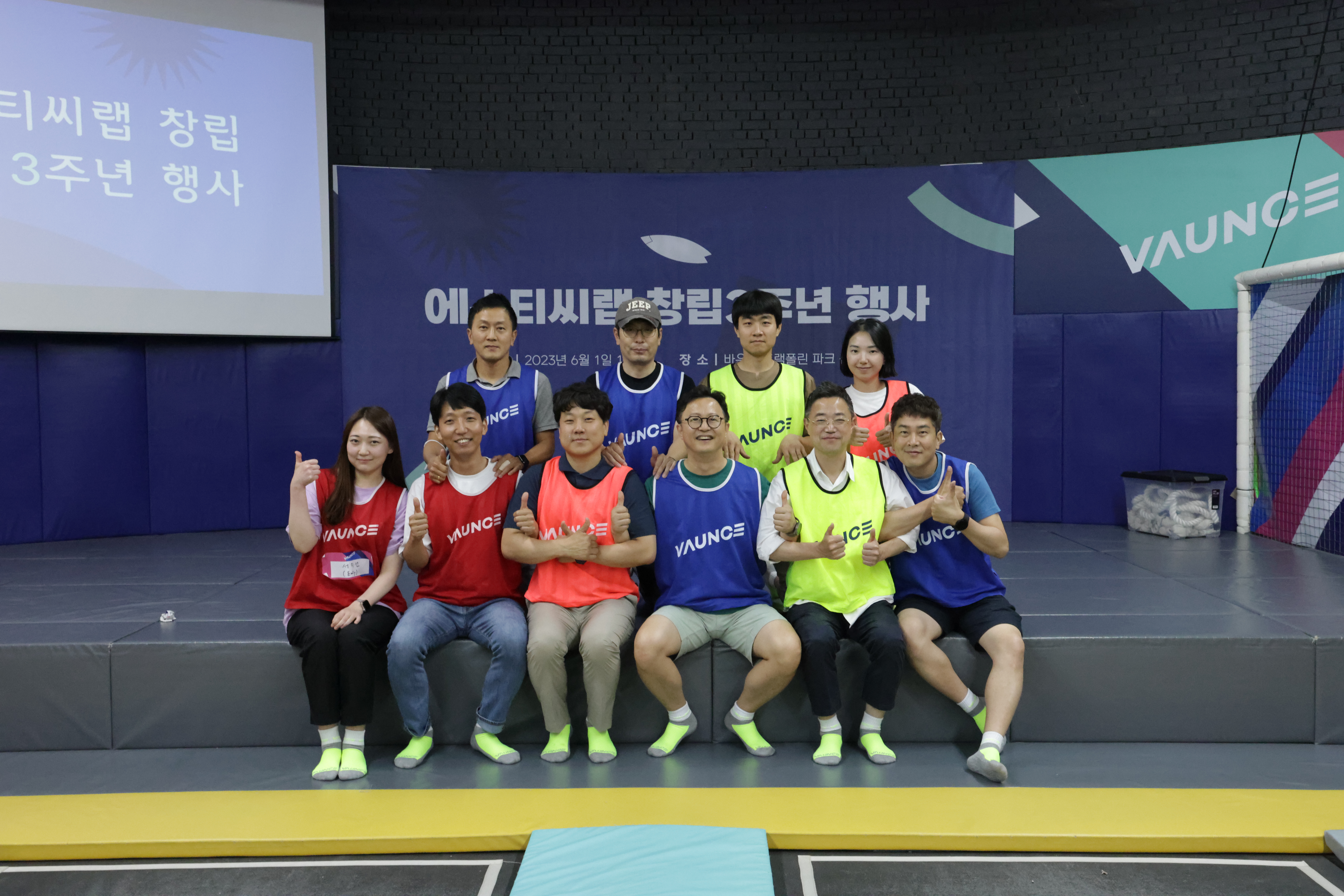 10명의 사람들이 앞뒤 2줄로 앉아 '엄지척' 포즈를 취하고 있다.
