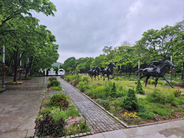'서울숲' 글자 조형물과 함께 보이는 말 조각상들, 주변에는 다채로운 꽃과 나무들이 조성되어 있음