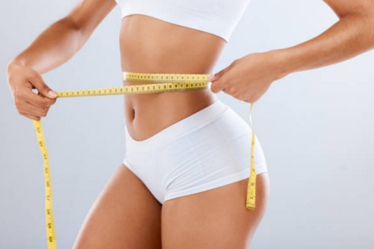 줄자로 허리둘레를 측정하고 있는 여성 사진