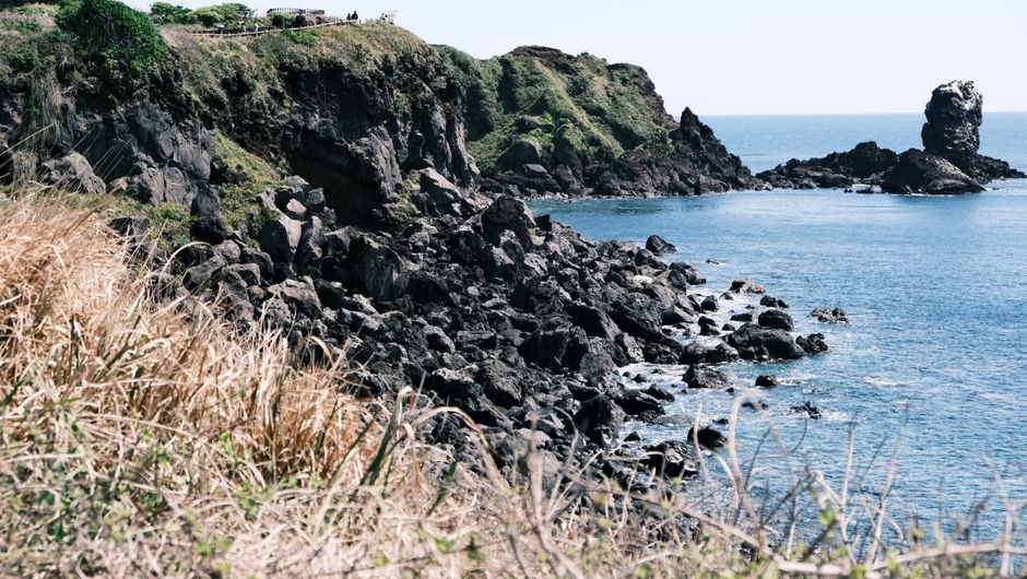 Explore the rugged cliffs and serene waters of Jeju Island's picturesque coastline.