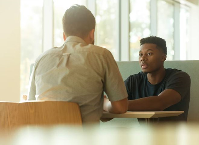 두 사람이 마주보고 앉아 대화하는 사진