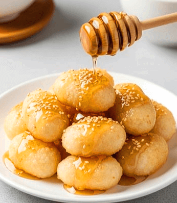 하얀 접시에 찰떡이 가득하고, 그 위에 꿀이 떨어지고 있다.