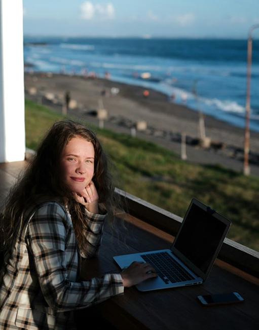 바다가 보이는 카페에서 노트북으로 일을 하는 여성 사진