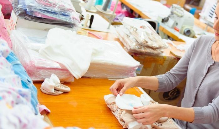 의류 제작 공장 작업장에서 의류를 접는 소상공인 여성