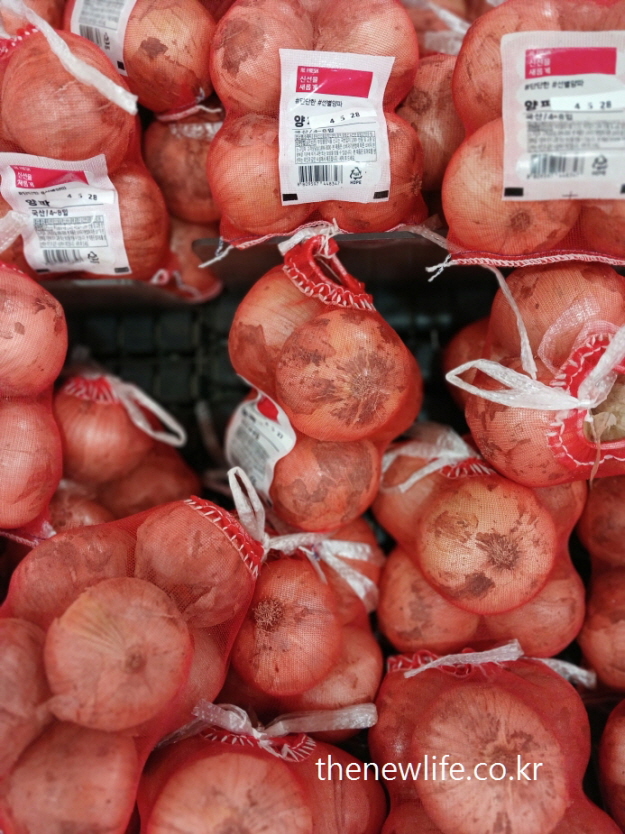 망에 담긴 양파들이 마트에 진열된 모습 &ndash; 뱃살 빼는 최고의 음식 실천에 포함된 중요한 재료입니다.