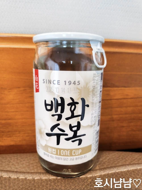 백화수복 원컵 한 병이 테이블 위에 세워져 있는 모습. 180ml 소용량 청주의 라벨과 디자인이 선명하게 보이는 제품 근접 사진