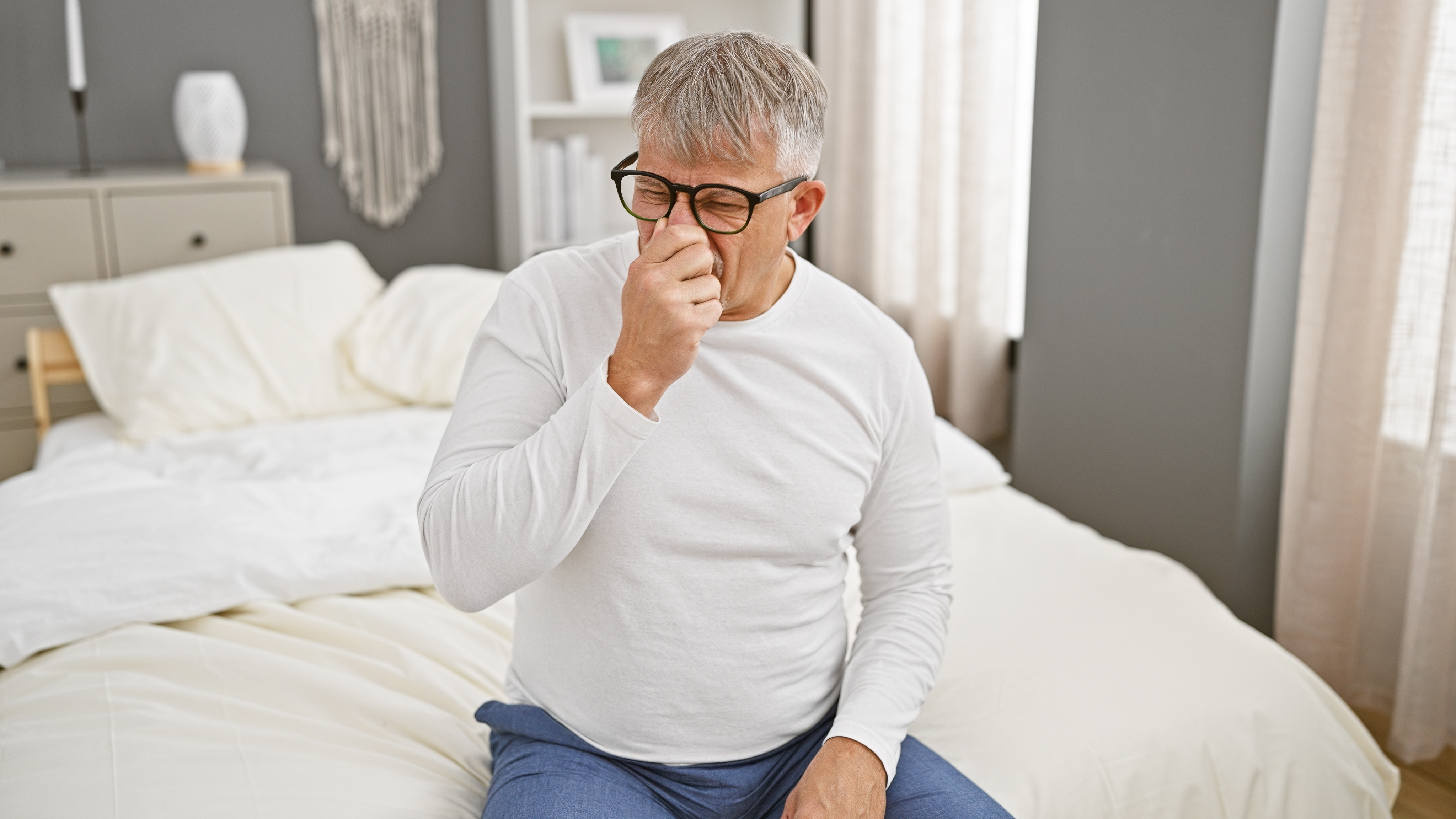 장마철 침실에서 악취를 느끼는 남성, 여름철 집안 냄새 문제를 표현한 이미지