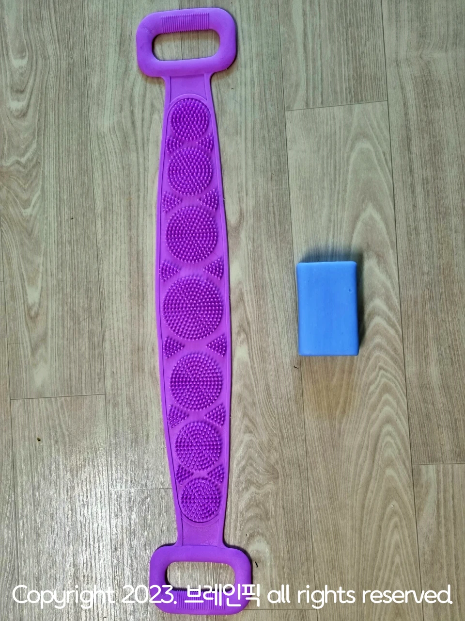 보라색 실리콘으로 이루어진 기다란 면에 돌기가 무수히 많고, 그 옆엔 하늘색 네모난 세탁비누가 있다