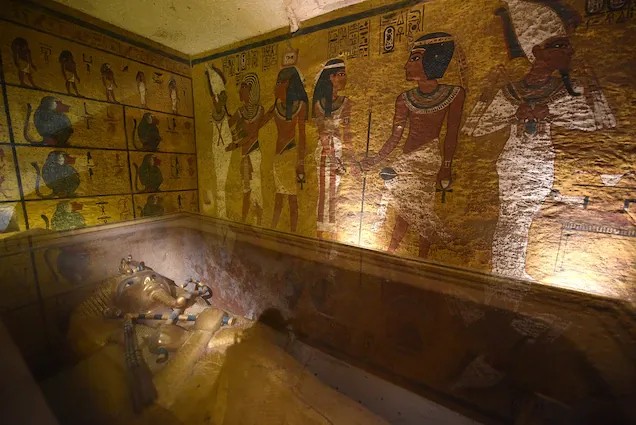 투탕카멘의 미라가 안치된 석관 앞 벽면에 여러 이집트 신들이 그려져 있는 무덤 내부. 색이 잘 보존된 벽화와 부장품의 흔적이 확인된다.