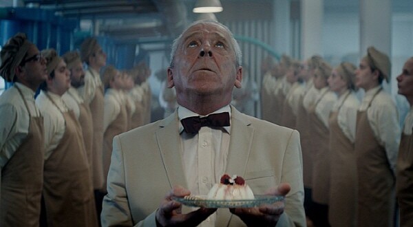 영화 《더 플랫폼》에서 정갈하게 세팅된 푸딩을 들고 위를 올려다보는 인물. 수많은 계층과 인간 군상이 늘어선 가운데, 이 장면은 ‘메시지’가 위로 전달되길 바라는 마지막 희망을 상징한다.