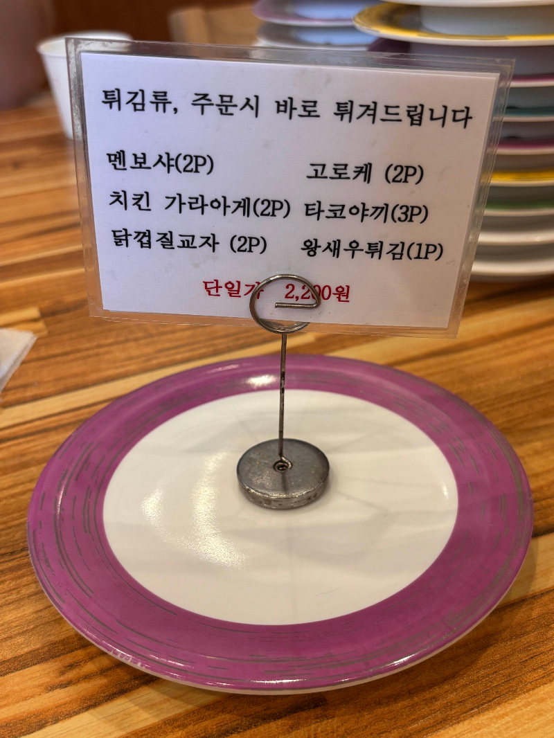 자주 접시 위에 놓인 튀김류 메뉴 안내판
Tempura menu card on a purple K-sushi plate