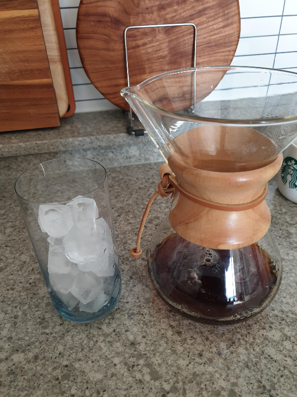 테이블 위에 얼음컵과 얼음이 녹은 커피 추출액이 담긴 케멕스 드리퍼가 놓여 있다.