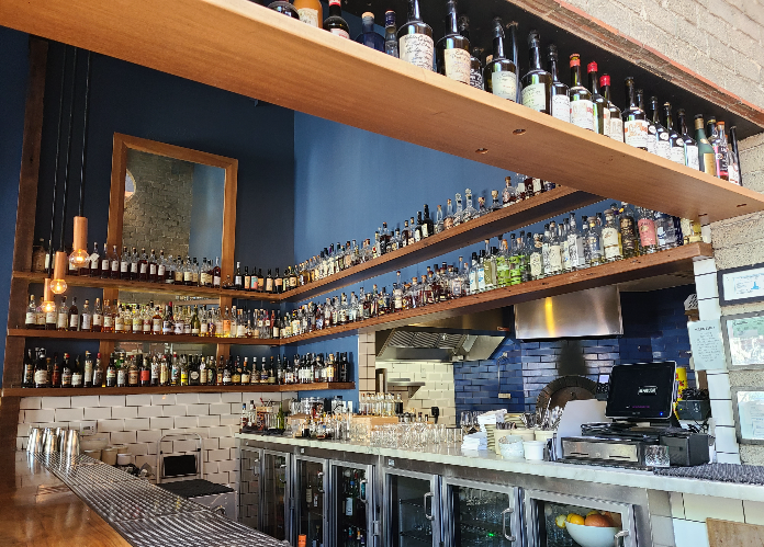 Republique Cafe Bakery의 내부. 다양한 종류의 위스키가 선반에 진열되어 있다. 선반은 총 3층이고, 그 아래쪽으로는 간단한 음식을 할 수 있는 바가 있다.