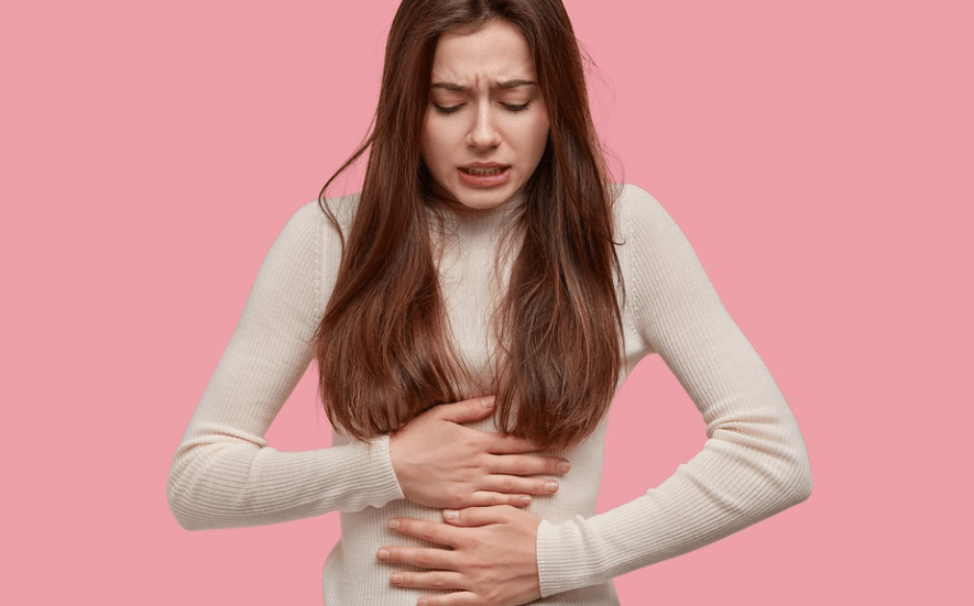 생리통이 심한 이유로 양 손바닥으로 배를 감싸며 고통스러워 하고 있는 여성