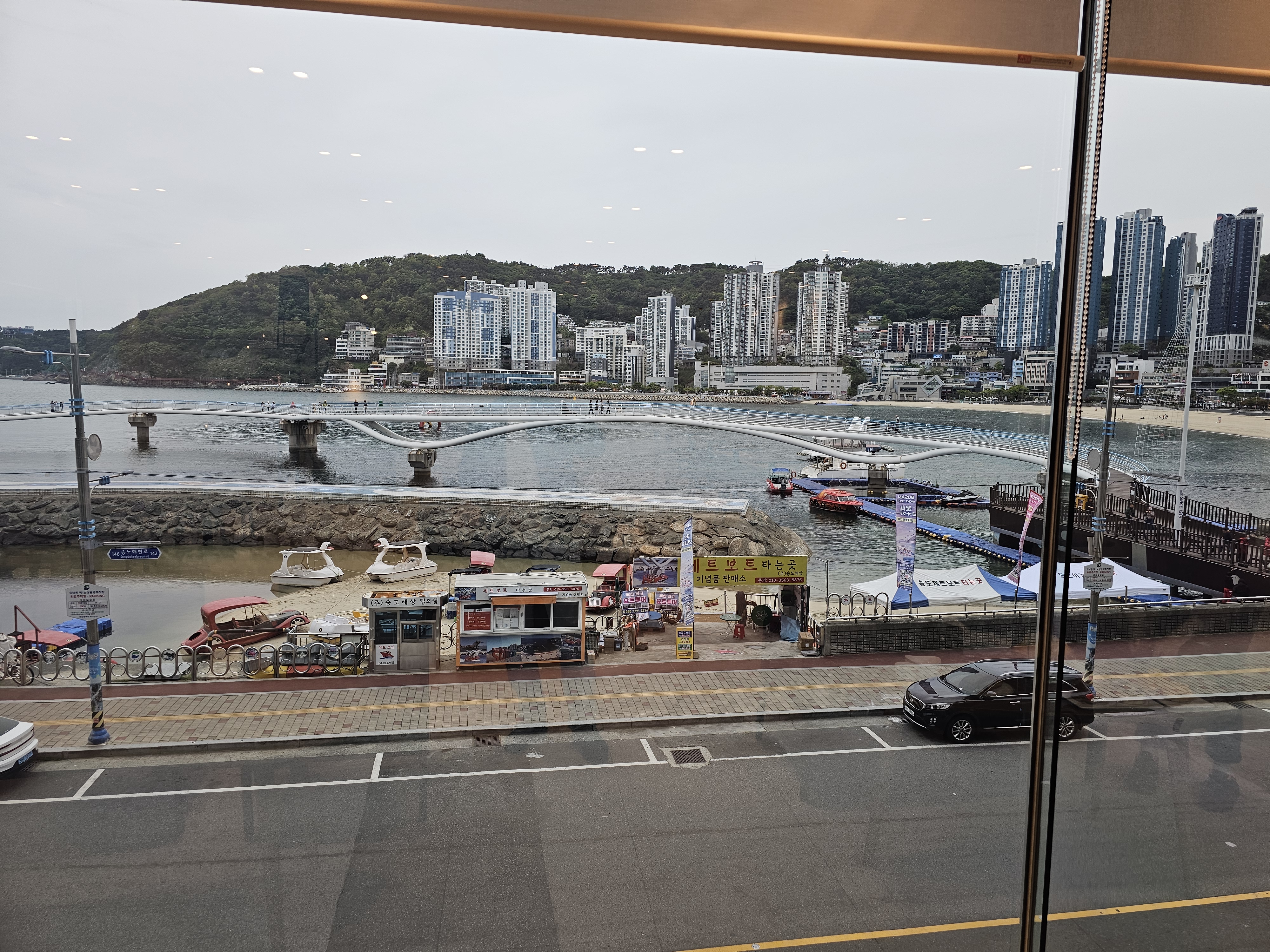 오그남 통창 너머 송도해수욕장 바다뷰 — 해변과 곡선 보행교, 오리배
