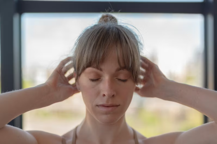 눈을 감고 머리를 감싸며 어지럼증을 느끼는 여성