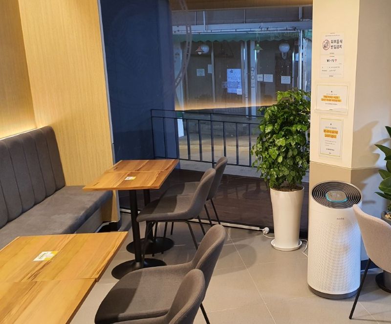 카페 테이블 모서리에 깔끔하게 부착된 와이파이 안내 스티커 근접 사진. 손님의 불필요한 이동과 반복적인 질문을 70% 이상 줄여주는 '친절의 자동화'와 코팅지 경영의 디테일을 보여줌.