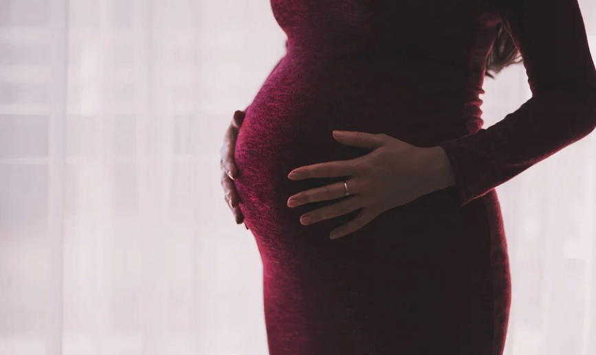 임산부가 두 손으로 자신의 배를 만지고 있다