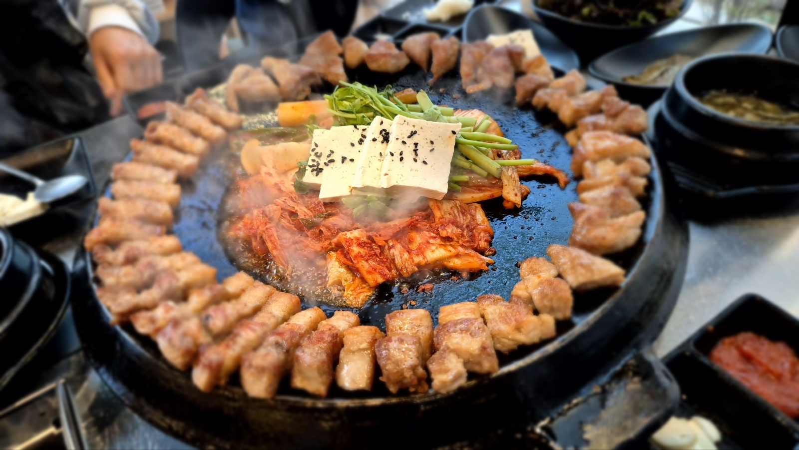 잘구어기 고기위로 김치와 두부 미나리가 한가득 올라가 있다.