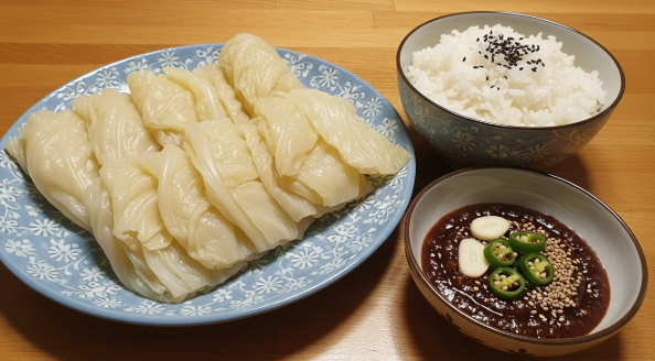 쪄낸 양배추, 밥, 특제 쌈장이 나무 트레이 위에 정갈하게 담겨있는 모습