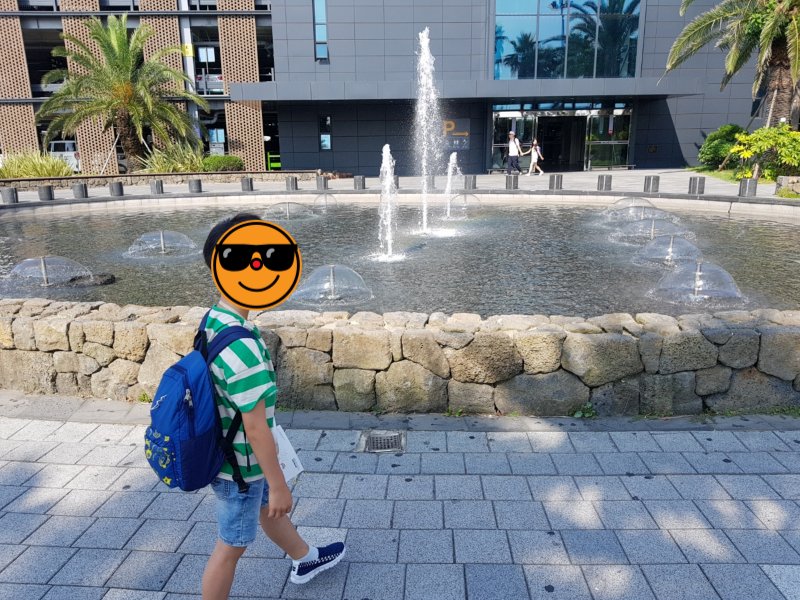 탁송 차량을 찾으러 광장 분수대 앞을 지나는 아이의 사진