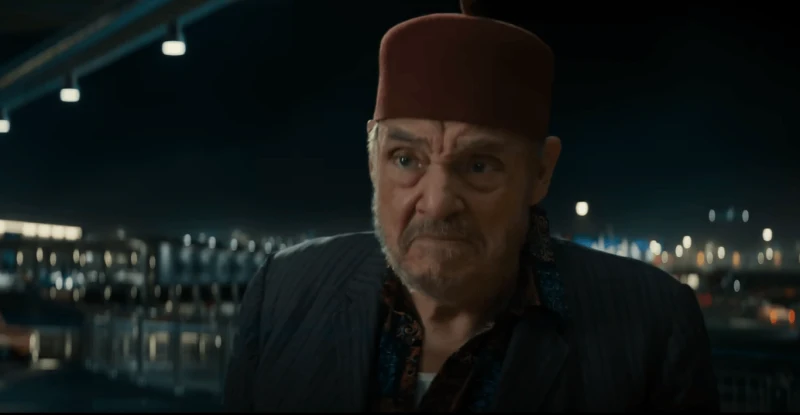 어느 도시를 배경으로 중동국가의 모자를 쓰고 입을 굳게 다물고 있는 살라