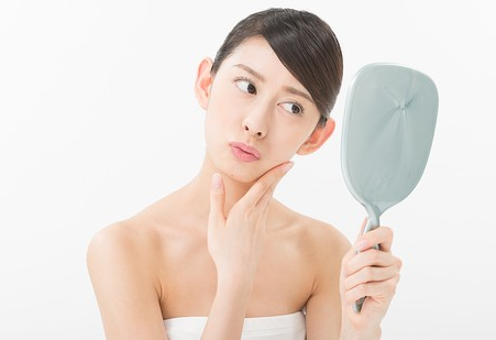 위험한 점이 있을까 봐 거울을 들여다보는 여성