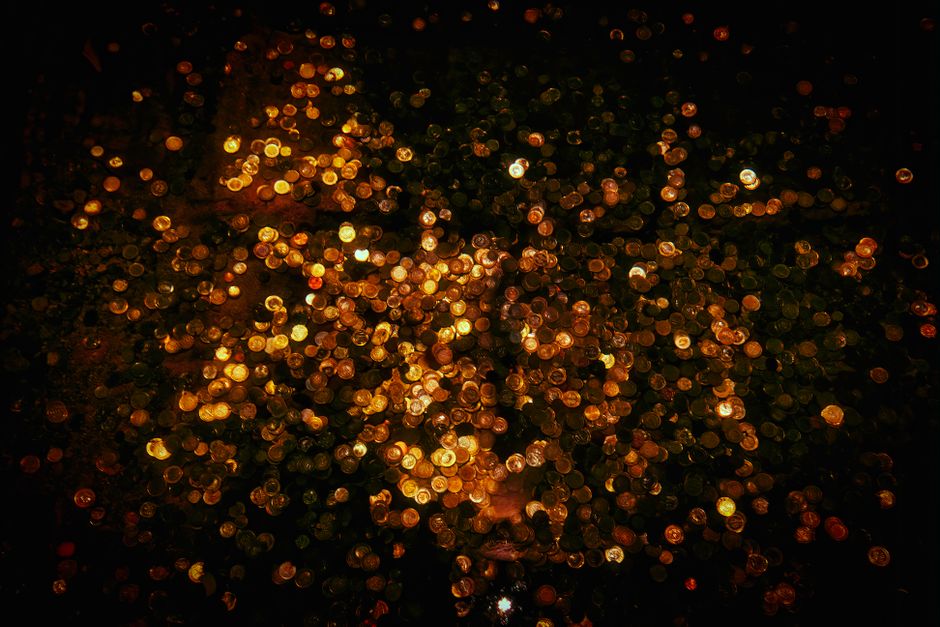 A mesmerizing display of shimmering golden coins sparkling in the dark, creating an abstract and enchanting visual effect.