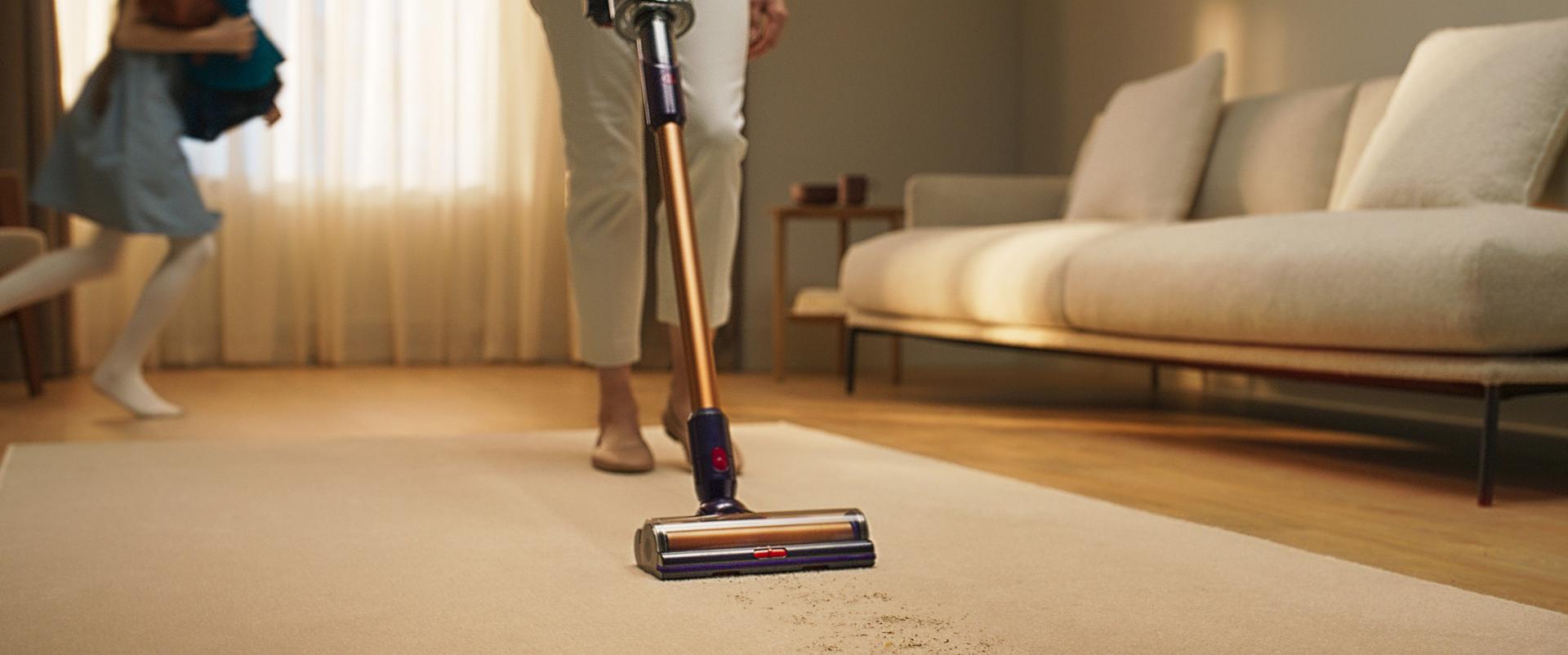 A person demonstrating the use of a wireless vacuum cleaner in a clean, bright living room, showcasing different cleaning