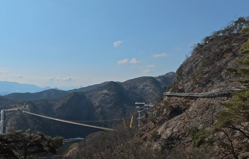 소금산의 절벽의 곡선을 따라 데크가 쭉 이어지고 있습니다. 그리고 이윽고 노란색 울렁다리로 이어지고 있는 모습입니다.