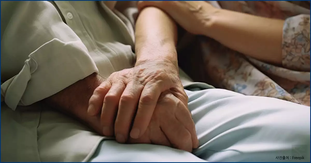 두손 맞잡은 어르신과 보호사