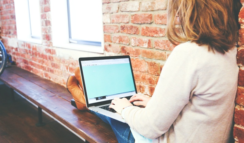 A female international student sitting with a laptop, checking exchange rates or managing overseas transfers online while studying in the U.S.