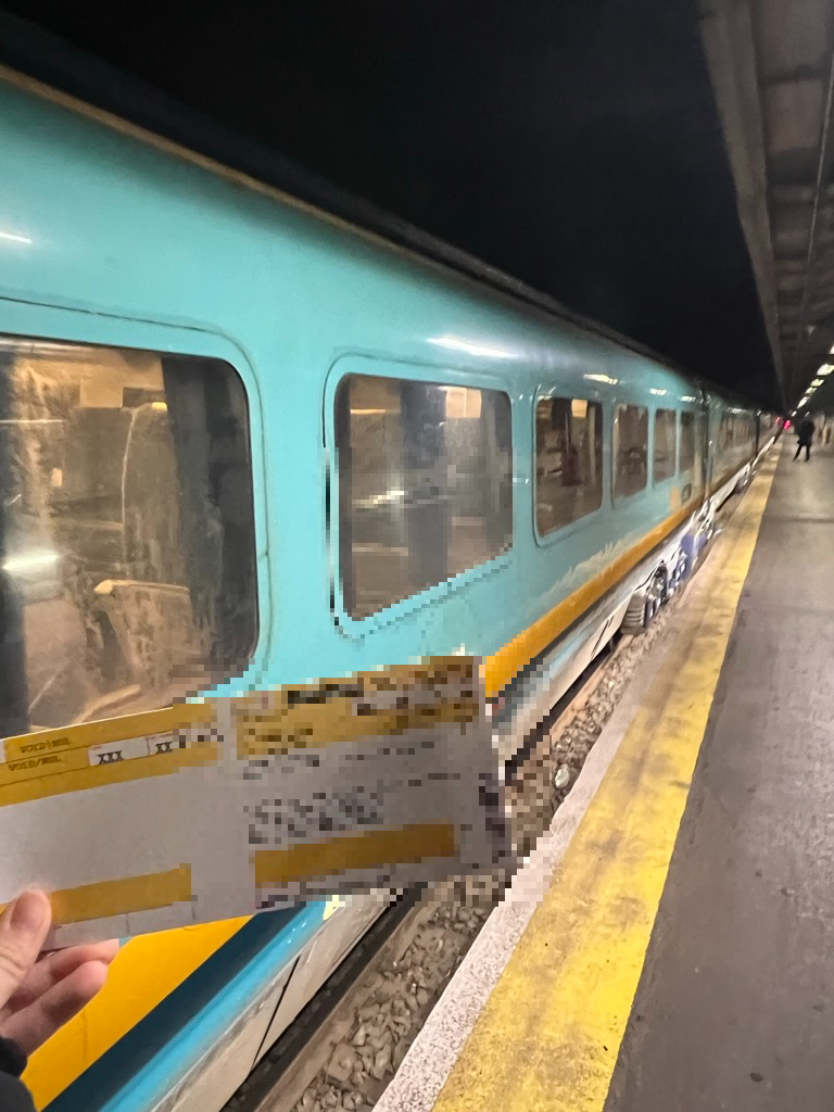 민트색의 기차 앞에 노란색 기차표를 들고 있는 사진이다.