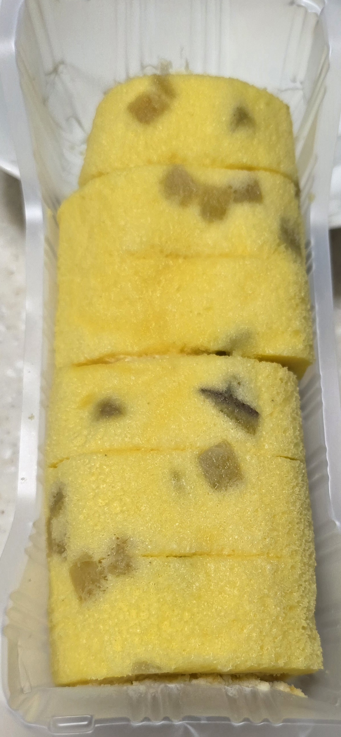 포장을 개봉한 일본 로손 고구마 모찌 롤케이크 여섯 조각과 노란색 시트에 박힌 고구마 조각