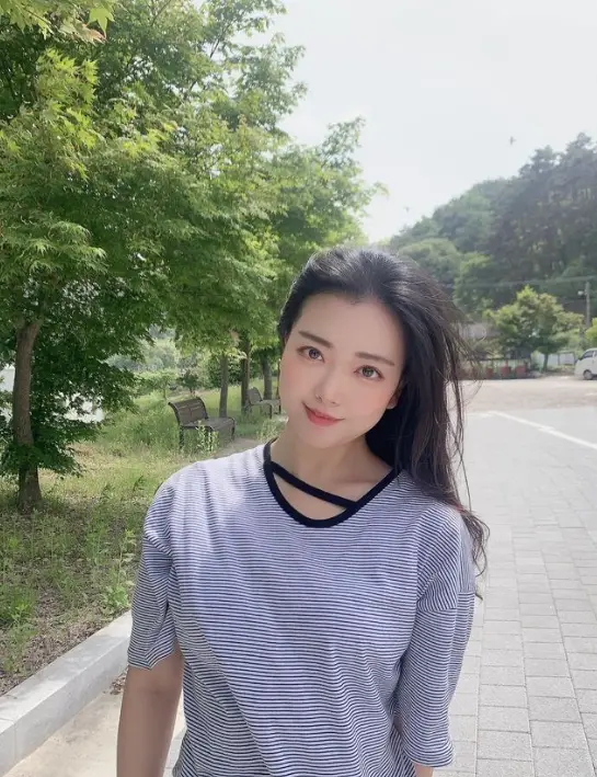 현역가왕- 야외 초록색 공원 검은 긴머리를 풀어헤치고 긴팔 흰색티를 입고 정면을 바라보며 미소짓는 요요미