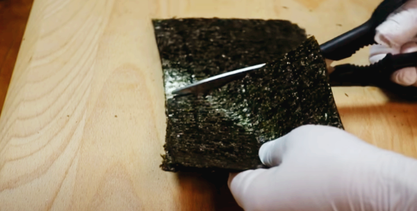 김밥용 김을 꼬마김밥의 크기에 맞게 두 번 자르고 있습니다