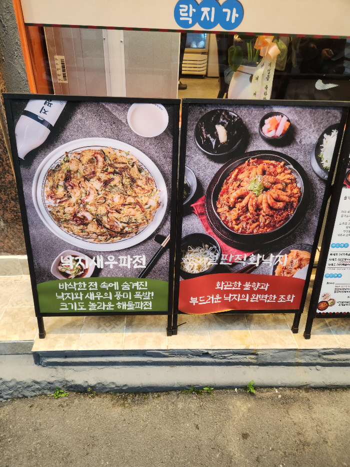 락지가의 메뉴 낙지새우파전과 철판직화낙지에 대한 메뉴 설명이 적혀 있는 입간판
