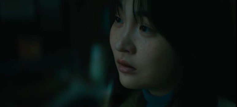 어두운 분위기 속에서 창백한 얼굴로 깊은 생각에 잠긴 여성