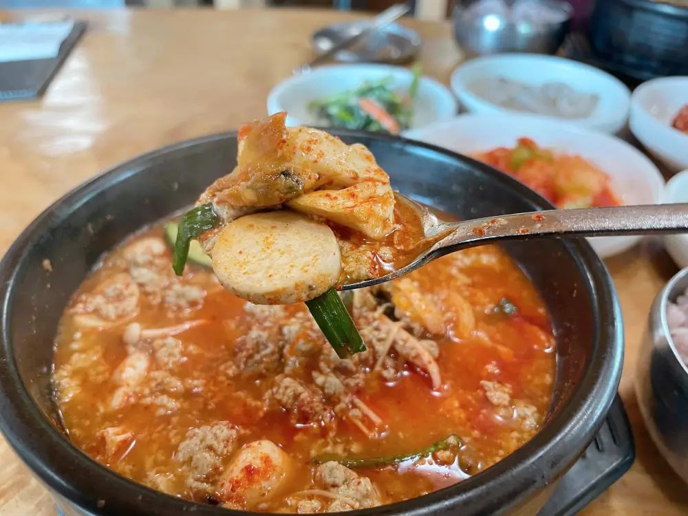뚝배기에 빨간 순두부탕에서 두부를 크게 한숟가락 뜬 모습