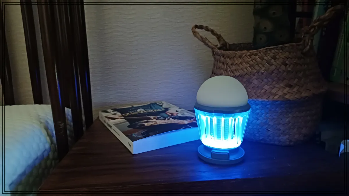 침대-옆-협탁에-하와스-캠핑랜턴이-푸른빛으로-켜진-상태로-책과-라탄-바구니가-함께-배치되어-있는-사진