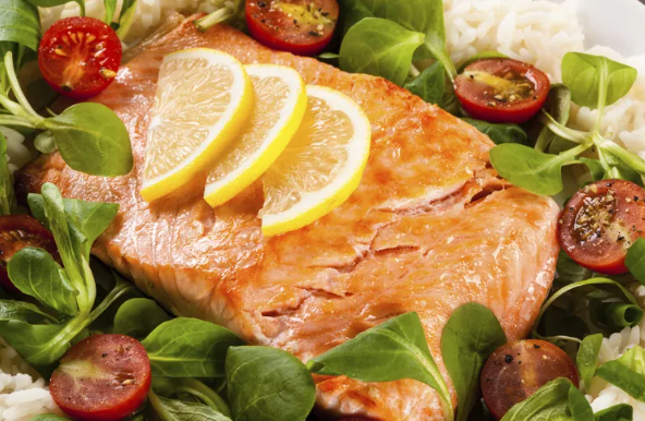 방울토마토, 쌀, 레몬 조각을 곁들인 시금치 위에 올려진 연어