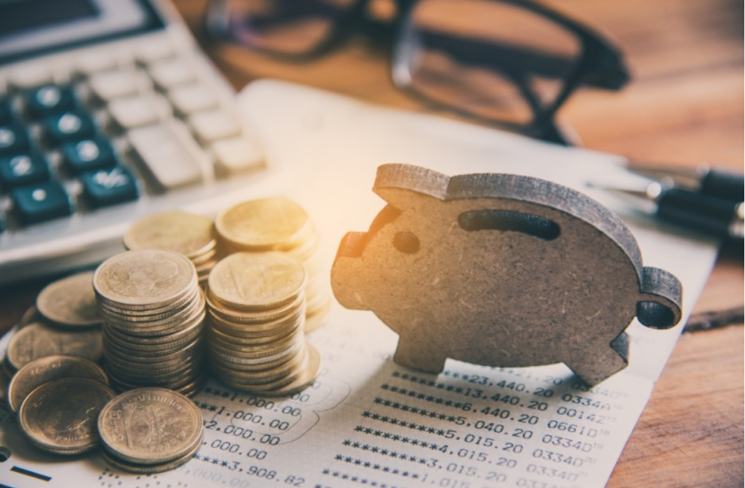 돼지 저금통과 동전들이 쌓여있다.