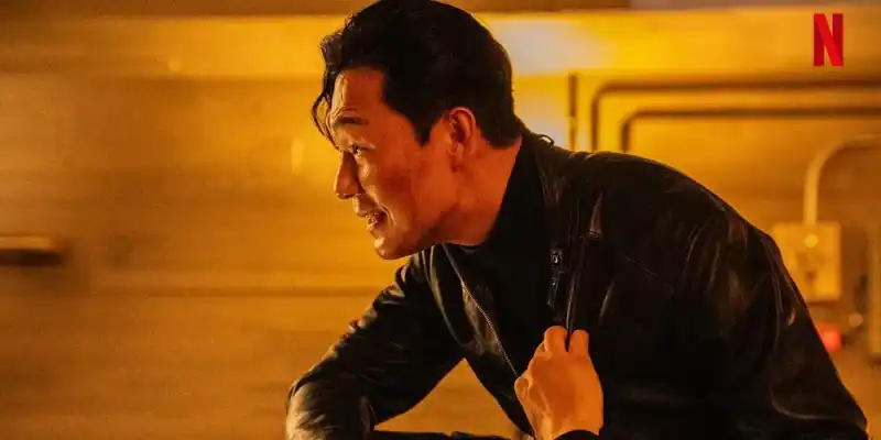 어느 건물을 배경으로 검은색 가죽자켓을 입고 누군가를 노려보고 있는 악랄한 사채업자 김명길