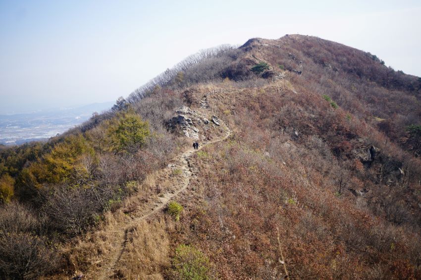 멀리 원적봉까지 뒤돌아 본 걸어온 아득한 능선길, 두 사람 걸어오고 있음, 엷게 푸른 하늘,