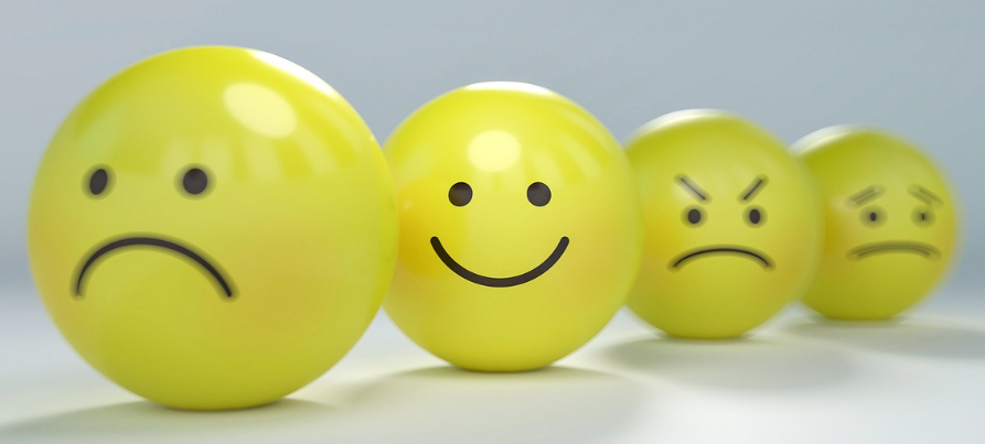 다양한 감정을 표현한 노란색 이모지 공들, 웃는 얼굴을 중심으로 슬픔과 분노 표정이 나란히 배치된 모습