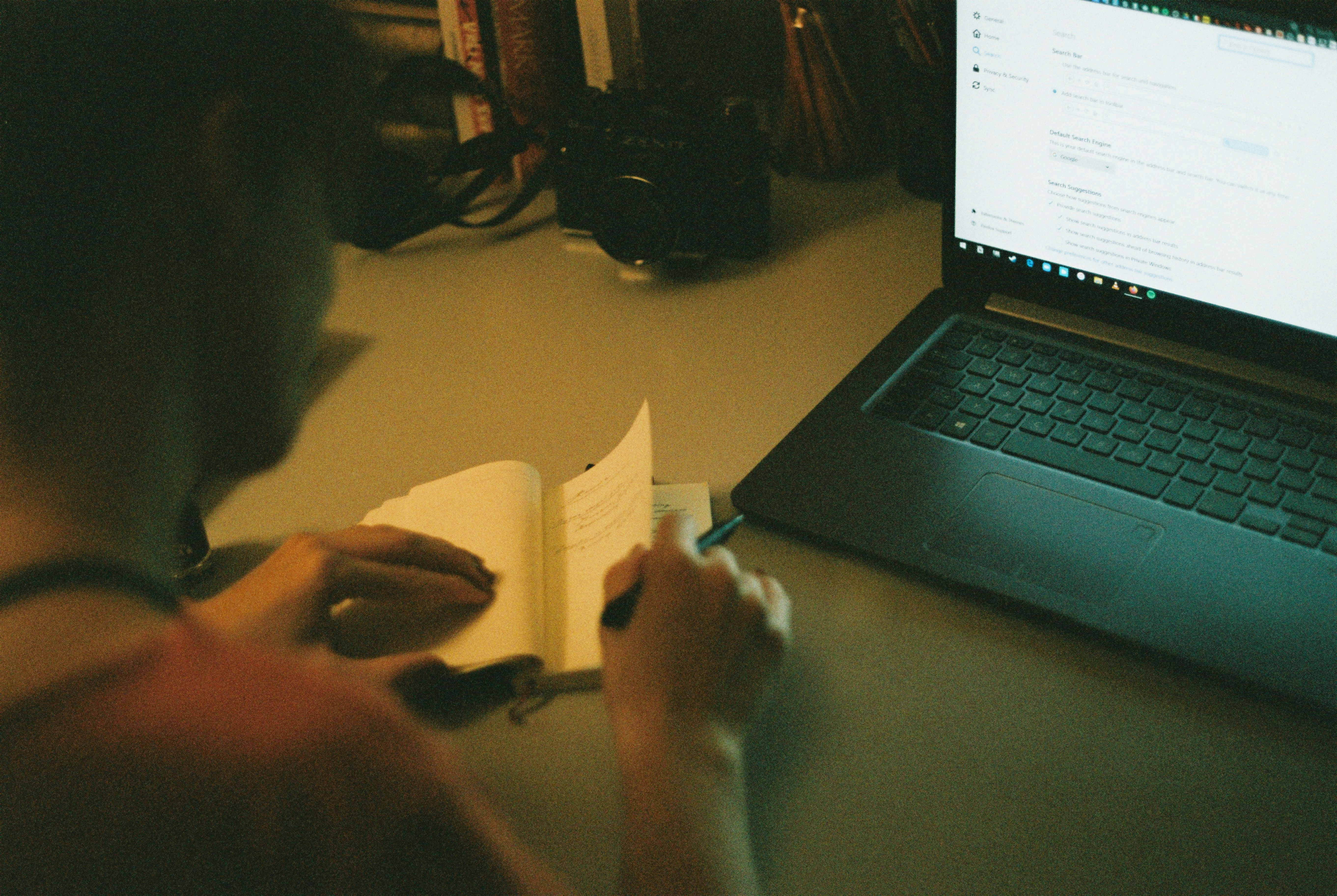 person writing on a laptop with books nearby