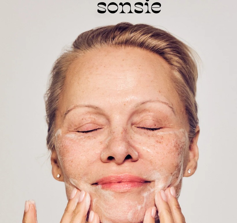 sonsie brand - woman washing her face with foam cleaser smiling